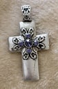 Silver Cross Pendant with Purple Rhinestones Close Up on Textured Background