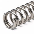 A silver cylindrical metal spring with flat ends, isolated on a white Royalty Free Stock Photo