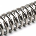A silver cylindrical metal spring with flat ends, isolated on a white Royalty Free Stock Photo
