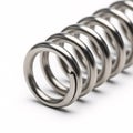 A silver cylindrical metal spring with flat ends, isolated on a white Royalty Free Stock Photo