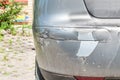 Silver damaged and broken car with dented aluminum metal body scratched and peeling paint from crash accident or collision