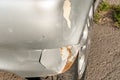 Silver damaged car in crash accident or collision with scratched paint and dented rear bumper metal body