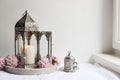 Silver decorative cup of tea, pink cherry tree blossoms and glowing Moroccan lantern on linen table cloth near window Royalty Free Stock Photo