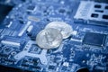 Silver Digital Cryptocurrency Coin on Blue Computer Motherboard.