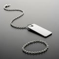 A silver dog tag hangs on a metallic chain against a smooth, dark surface. The chain forms a gentle Royalty Free Stock Photo