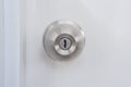 A silver doorknob mounted on a white door. Royalty Free Stock Photo