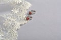 Silver earrings with red glass hearts with delicate ecru lace on a light gray background. space for text Royalty Free Stock Photo