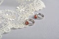 Silver earrings with red glass hearts with delicate ecru lace on a light gray background. space for text Royalty Free Stock Photo