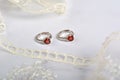 Silver earrings with red glass hearts with delicate ecru lace on a light gray background. space for text Royalty Free Stock Photo