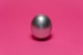 Silver egg on a dark pink background. Abstract Easter background Royalty Free Stock Photo