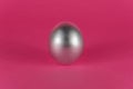 Silver egg on a dark pink background. Abstract Easter background Royalty Free Stock Photo