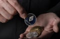 Silver ethereum coin of cryptocurrency in male hand palm over black background, close up. Eth putting into crypto pile Royalty Free Stock Photo
