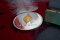 Silver Ethereum coin lying on red wool surface