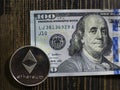 Silver Ethereum on US dollars. Digital currency close-up on a wooden background.Real coins of bitcoin on banknote of one hundred