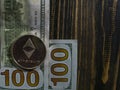 Silver Ethereum on US dollars. Digital currency close-up on a wooden background.Real coins of bitcoin on banknotes of one hundred