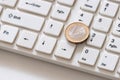 Silver euro coin with a gilded border close-up lies on the key with the number one. White computer keyboard. Shareholders on the Royalty Free Stock Photo