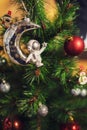 A silver figurine of an astronaut and Christmas balls hang on a green spruce. Festive background. Defocused image