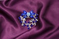 Silver flower brooch with blue diamonds on silk fabric Royalty Free Stock Photo