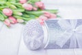 Silver Easter egg, gift box and pink tulips on a white wooden background Royalty Free Stock Photo