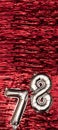 Silver foil balloon number 78 on a background of red tinsel decoration. Birthday greeting card, inscription seventy