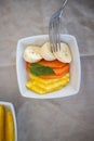 Silver fork pocking sliced fruit on square white plate