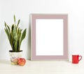 Silver frame mockup with plant pot, mug and apple on wooden shelf Royalty Free Stock Photo