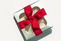 Silver gift box with red ribbon bow isolated on white background. Copy space, flatlay, top view Royalty Free Stock Photo