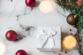 Silver gift on marble background with red Christmas balls and Christmas wreath. The concept of New year and Christmas, lights