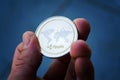 Silver gold ripple coin in hand, cryptocurrency investing concept