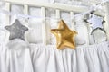 Silver, gold and white star shaped pillows on a white baby cot Royalty Free Stock Photo