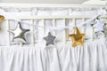 Silver, gold and white star shaped pillows on a white baby cot Royalty Free Stock Photo