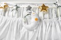 Silver, gold and white star shaped pillows and sleeping moon cushion on a white baby cot