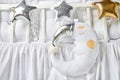 Silver, gold and white star shaped pillows and sleeping moon cushion on a white baby cot Royalty Free Stock Photo