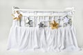 Silver, gold and white star shaped pillows on a white baby cot