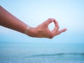 Silver and golden flash tattoo on female hands over sea or ocean background. Woman practicing yoga. Gyan Mudra.