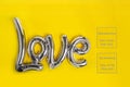 Silver gray foil balloons in the form of a word Love on yellow background. Happy Valentine`s day. Love concept. Trend