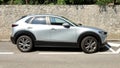 Silver gray Mazda CX30 on stonewall wall background.