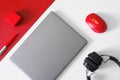 Silver gray laptop or ultrabook, fountain pen, red computer mouse, red box and black headphones on a red and white background. The Royalty Free Stock Photo