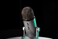Silver grey USB condenser microphone with adjustable tabletop stand sitting on a white table