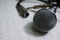 Silver Grille microphone with XLR cable on white leather SELECTIVE FOCUS Royalty Free Stock Photo