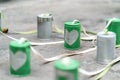 Silver heart on green cans connected with rope on cement floor. Royalty Free Stock Photo