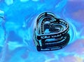 Silver Heart in puddle of water with reflection. Royalty Free Stock Photo