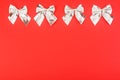 Silver holiday bows on a red background.