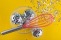 Silver holiday decorations. Party invitation card, yellow background, copy space for text. Top view on shining small disco balls Royalty Free Stock Photo