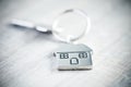 Silver home shaped keychain with key on wooden background Royalty Free Stock Photo