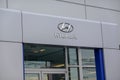 Silver Hyundai logo on a gray wall above the entrance of a automobile dealership