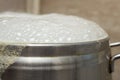 silver inox pot boiling over with white bubbles