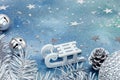 silver jingle bells and christmas tree branches with white sledge on blue background