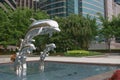 Silver jumping dolphin sculptures in public park in urban square 29 June 2004