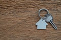 Silver key house with house shaped keychain on vintage wooden table background. Royalty Free Stock Photo